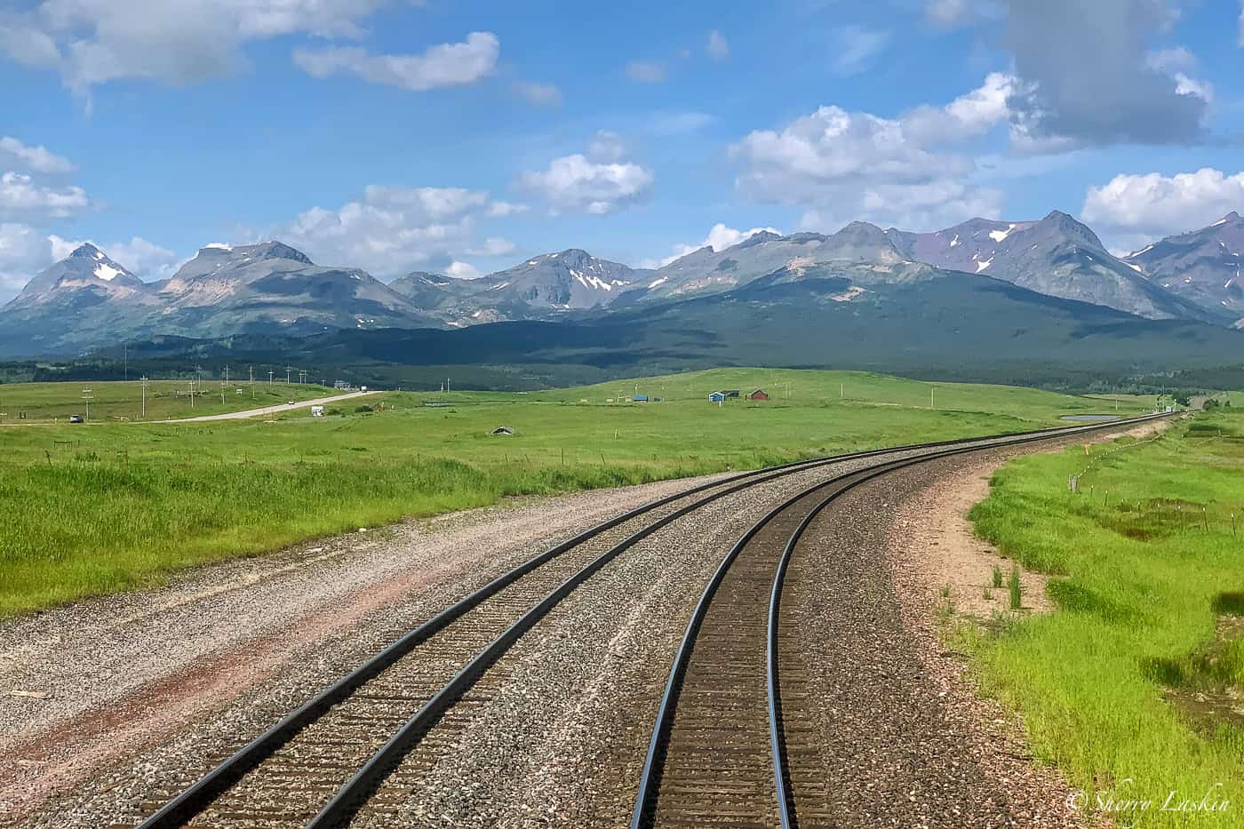 View from the rear of the train of Glacier National Park mountains and train tracks.