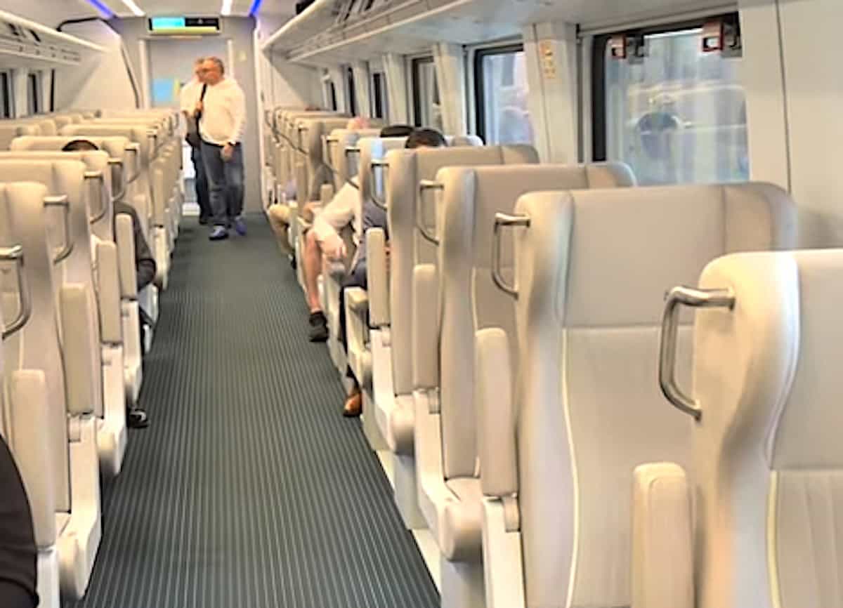 View of Premium class seating with off-white leather chairs and a few people boarding.