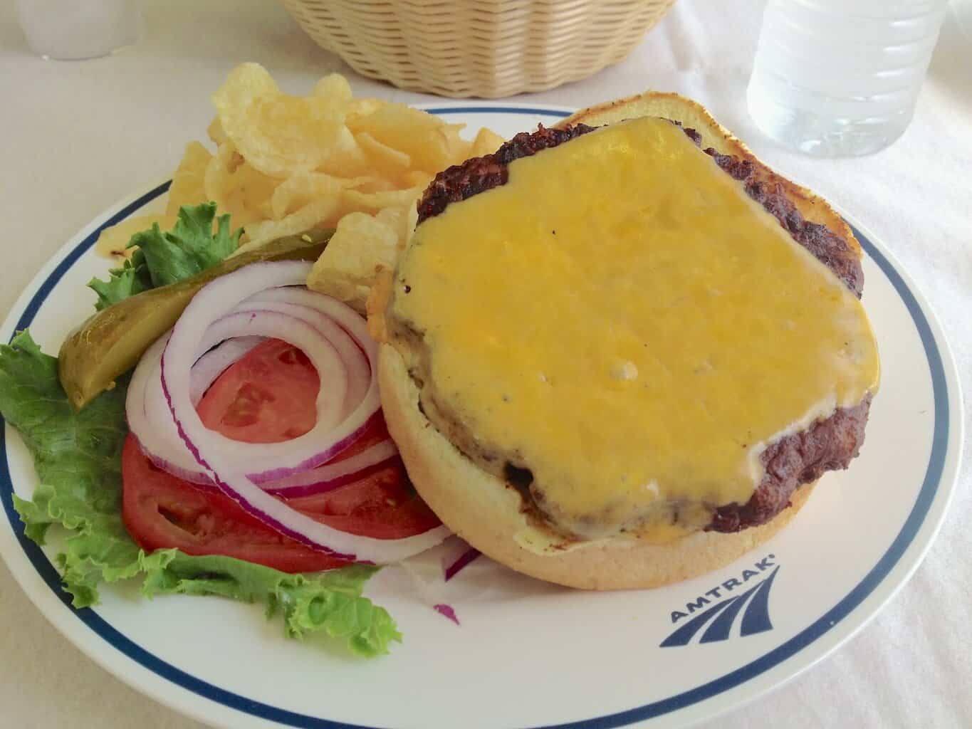 Amtrak angus cheeseburger and chips with onion and tomato served in the dining car.